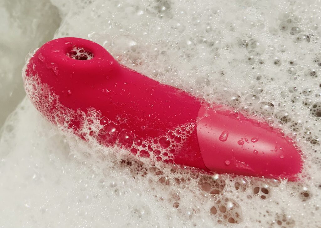 Womanizer Enchance in the tub, surrounded by bubbles